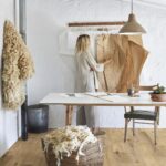 photo d'une femme dans un atelier avec un sac de laine de mouton posé au sol et des échantillons de peaux au mur