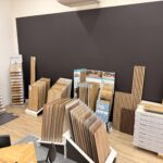 photo d'un showroom contenant de nombreux échantillons de revêtements de sols de type parquets et vinyles, avec une table et des chaises au centre de la pièce.
