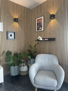 photo d'un fauteuil moderne en tissu gris posé devant un mur au bardage bois fin et une affiche du film Pulp Fiction au mur